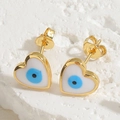 Macro view of heart-shaped evil eye stud earrings with blue enamel and gold plating - Heart Stud Earrings