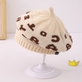 Detaillierte Strickstruktur einer beigen Kinderbaskenmütze mit braunem Jacquard-Muster - 1-3 Jahre / Beige
