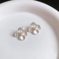 Macro shot of minimalist white flower stud earrings with zircon centers on ceramic - Cream