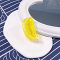 Detailed view of yellow resin lemon slice accessory on a white decorative display plate - Half Lemon Slice