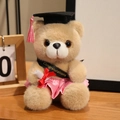 Abschluss-Teddybär mit rosa Rock, schwarzem Doktorhut und Glückwunschschärpe - Kamelfarbener Bär-Rosa Kleidung / 18cm