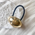 Nahaufnahme von goldenem Haarband in Kieselsteinform mit schwarzem Gummiband auf Stoff - Glattes Oval / Goldenes Oval