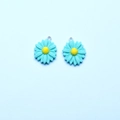 Detailed macro view of mint green resin daisy charms with yellow centers and silver loops - Emerald