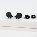 Macro shot of minimalist matte black hedgehog stud earrings on a white stone base - Hedgehog / Black