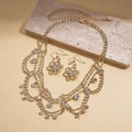 Close-up of golden fringe flower necklace and earrings set with sparkling rhinestones - Gold