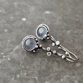 Détails macro des boucles d'oreilles pierre de lune bleue au design branche vintage - Blanc