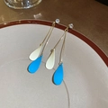 Close-up of gold chain earrings with blue and white resin drops on a ceramic plate - Gold-Blue White Double Bead-Double Chain