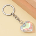 Macro shot of 3D iridescent resin heart keychain with shiny silver metal ring and chain - White