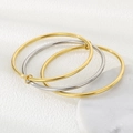 Detail von drei ineinander verschlungenen 3mm Edelstahlarmreifen in Gold- und Silberfinish - 55mm / Dreifachringe (1 Stahl + 2 Gold)
