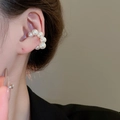 Dettaglio di un earcuff a C con perle bianche rotonde indossato sull'orecchio - Orecchini a clip (1 paio) / Bianco