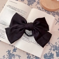 Classic large black satin bow hair tie placed on a book for a vintage aesthetic look - Bow Scrunchie / Black