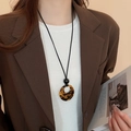 Retro tortoiseshell round pendant necklace with black cord on model in brown suit - Tortoiseshell Ring (14#) / 14# Necklace-Coffee