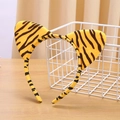 Detailed view of plush tiger print headband with cat ears on a wooden surface - Tiger