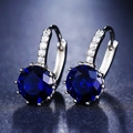 Macro view of blue round-cut zircon earrings with silver multi-claw setting and pavé inlay - Ear Buckle / Sapphire Blue