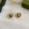 Elegant gold flower earrings featuring a faceted olive green zircon and crystal halo - 5077 Geometric Cross Zircon