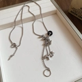 Gros plan d'un collier vintage argenté avec pendentif cheval sur un plateau bijoux - 12# Collier-Argent-Noir