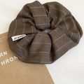 Close-up of brown striped fabric scrunchie with herringbone texture and woven logo tag - Hair Tie / Brown