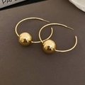 Gedetailleerd beeld van minimalistische gouden oorringen met een gepolijste metalen kraal - Grote Gouden Ring (Zilveren Naald)