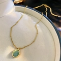 Elegante gouden ketting met ovale groene kattenoogsteen hanger op fluwelen achtergrond - Ketting-Groen