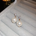Macro view of gold-plated pearl drop earrings with triangular cubic zirconia detail - Trapezoid Inlaid Zirconia Gold Pearl Earrings