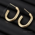U-shaped gold metal earrings with polished finish on black leather background - U-Shaped Glossy Hoop