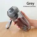Gros plan d'un shaker transparent gris avec dragonne et boule de mélange dans la main - Type AS (Corde sans logo) / Gris