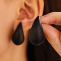 Matte black teardrop earring shown on ear to demonstrate size and minimal style - Black Matte Drop