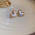 Close-up of heart-shaped gold earrings with pearlescent center on a ceramic tray - Pearl Heart Stud / White