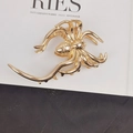 Detailed close-up of a high-shine golden metal spider hair claw clip on a book - Large Spider Hair Claw / Gold