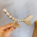 Dettaglio di un fermaglio per capelli in metallo dorato a forma di pesce con perle - Grande Coda di Pesce