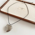 Close-up of vintage engraved silver heart pendant with black cord on display tray - Black Rope Silver Heart Pendant