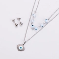 Detail view of a double-layered stainless steel evil eye necklace and silver ball earrings - Steel White