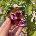 Detailed view of a hand holding a 7cm aura crystal skull with red rainbow luster - 7cm / Electroplated Red