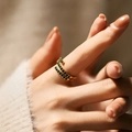 Detailed macro of a 18K gold spiral ring set with emerald green cubic zirconia stones - Adjustable Open / Green (KR0039)