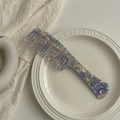 Macro shot of wide-tooth acetate hair comb with colorful tortoiseshell pattern on white plate - Dreamy Purple Long Handle Comb