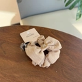 Dettaglio di scrunchie in cotone e lino beige con targhetta ovale a fiocco su legno - Elastico per Capelli con Fiocco Rosa Nude