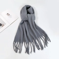 Detail of grey mohair scarf with tassels on a white background with a magazine - Gray