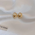 Minimalistische goldene Bohnen-Ohrstecker mit poliertem Finish auf elegantem weißem Seidengrund - Gold