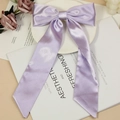 Elegant lavender satin bow hair clip with long ribbons in a minimalist setting - Purple