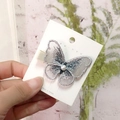 Silver-grey embroidered butterfly hair clip with a white pearl on a display card - Grey Embroidered Butterfly