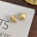 Macro shot of golden bean-shaped earrings featuring a matte brushed metal texture - Matte Gold