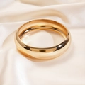 Dettaglio del bracciale a fascia larga dorata lucida su sfondo in seta bianco panna - Oro Piccolo