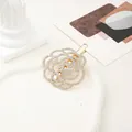 Gros plan d'une pince à cheveux rose dorée sertie de strass sur un socle élégant - Pivoine