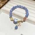 Dettaglio bracciale di perle con ciondolo gatto portafortuna e targhetta dorata - Blu scuro
