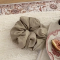 Detail of a large khaki puffy scrunchie on a cream blanket with cozy vintage decor - Khaki