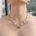 Detalle de un collar de cuentas de concha de colores con dijes de flores usado por una modelo - Serie Rosa Concha