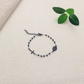 Detailed macro view of black beaded bracelet with cross pendant and religious medal charms - Black Priest