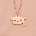 Macro view of rose gold graduation cap pendant necklace on soft pink silk fabric - Rose Gold