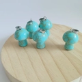 Five turquoise mushroom pendants with metal loops on a natural wooden display disk - Synthetic Blue Turquoise Gold Vein