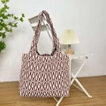 Detail of burgundy and beige wave knit tote bag hanging on a white chair in a cozy setting - Wave Jujube Red